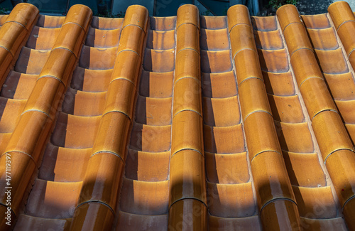 Overlapping rows of Orange ceramic roofing tiles texture covering building roof. Pattern background in horizontal orientation, Selective focus.