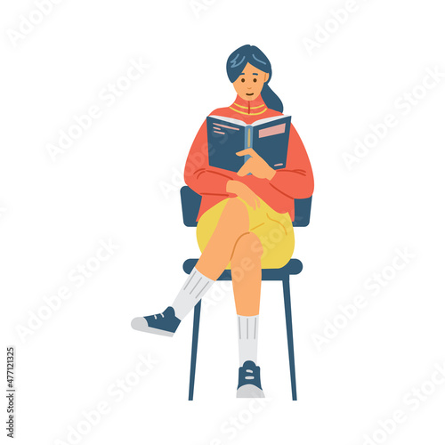 Pretty girl reads book sitting on chair, student studies scientific literature