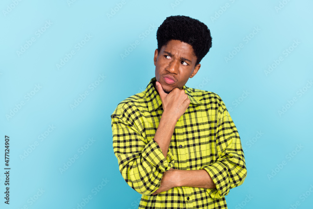 Photo of millennial brunette think guy look empty space wear yellow shirt isolated on blue color background Photo of millennial brunette think guy look empty space wear yellow shirt isolated on blue color background