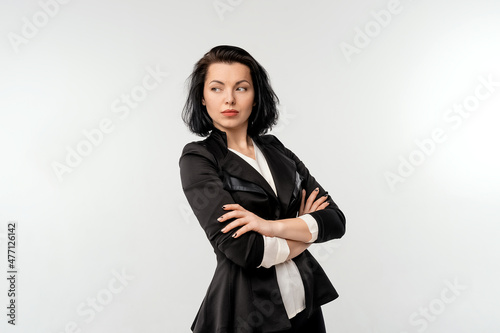 Confident young business woman with arms crossed, posing isolated over white background, wear black formal jacket white shirt. Achievement career wealth, business concept