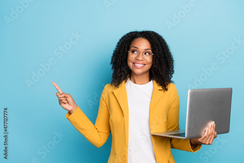 Photo of young afro woman happy smile indicate finger empty space advertise recommend sale computer isolated over blue color background