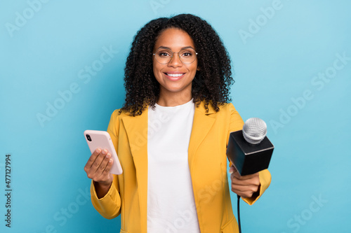 Photo of young african woman use smartphone journalist news interview speak isolated over blue color background photo