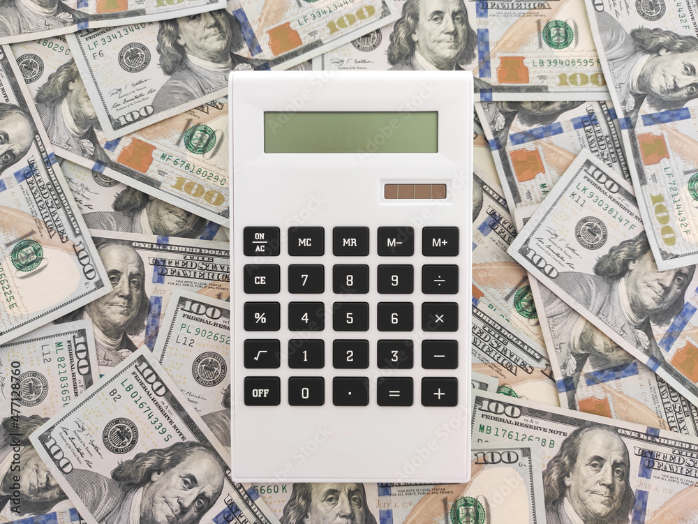 Calculator on one hundred dollars bills background Calculator on one hundred dollars bills background