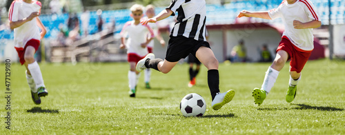 Fototapeta Naklejka Na Ścianę i Meble -  School Soccer Players Running After Ball and Kicking League Match. Group of Kids Footballers in a Duel. Soccer Players in  Sporty Jersey T-shirts and Turf Cleats