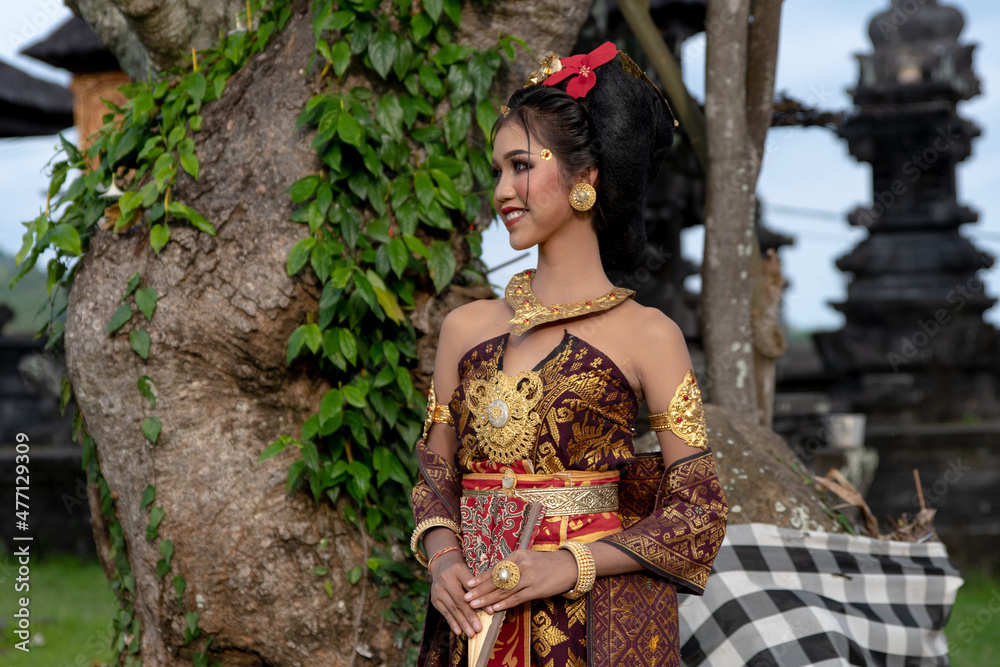 Young Balinese girl in traditional dress with a flower in hair, ocal temple in Bali, Indonesia. Young Balinese girl in traditional dress with a flower in hair, ocal temple in Bali, Indonesia.