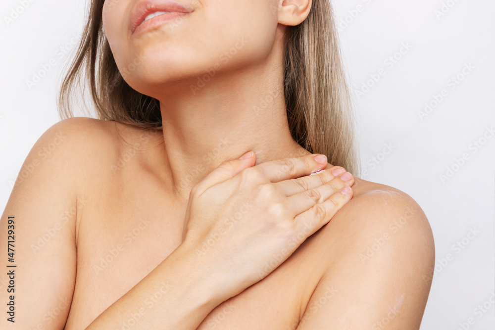 A cropped shot of a young blonde woman massaging her body with her hands using a cream to moisturize the skin isolated on a white background. Skin care