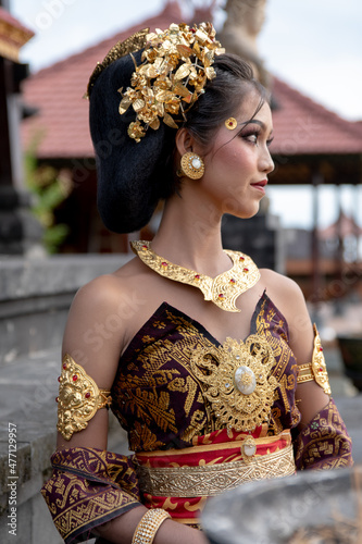 Young Balinese girl in traditional dress with a flower in hair, ocal temple in Bali, Indonesia. photo