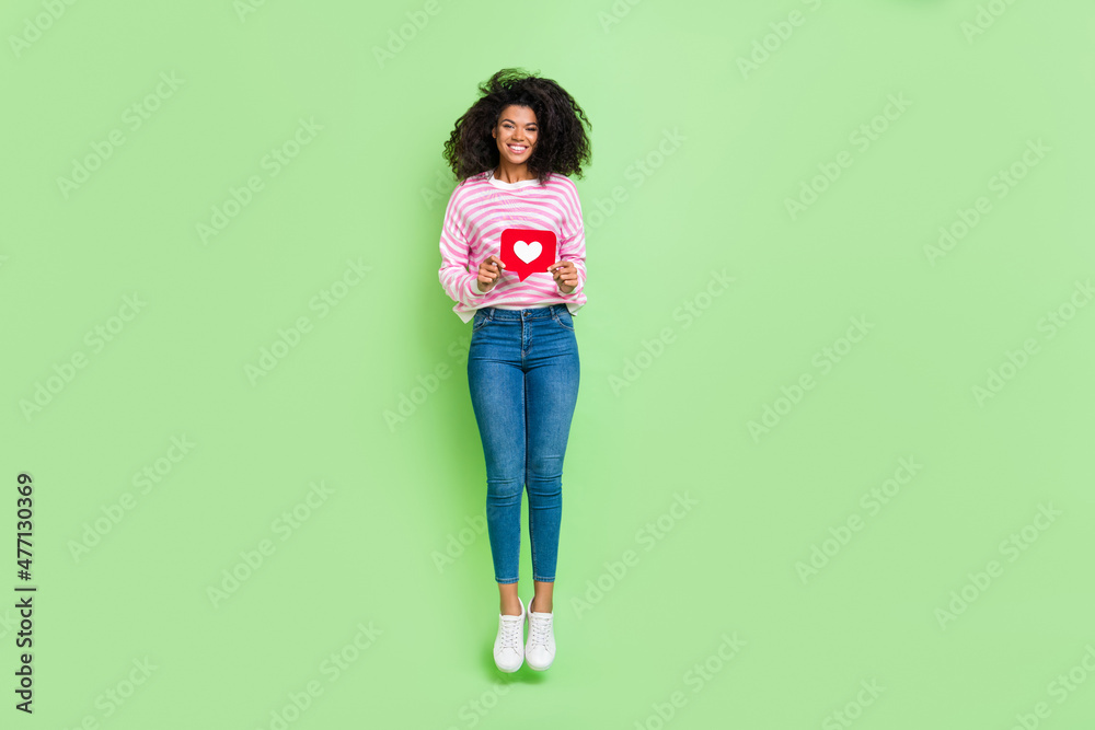 Full length body size view of attractive cheerful trendy girl jumping holding like heart isolated over bright green color background - obrazy, fototapety, plakaty 