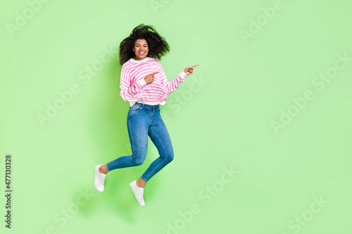 Full length body size view of attractive cheerful lucky girl jumping showing copy space isolated on bright green color background