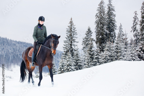 Young woman riding horse in mountains in winter.