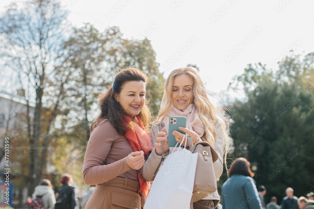 Fototapeta premium Senior female girlfriends discussing shopping while walking the city streets.