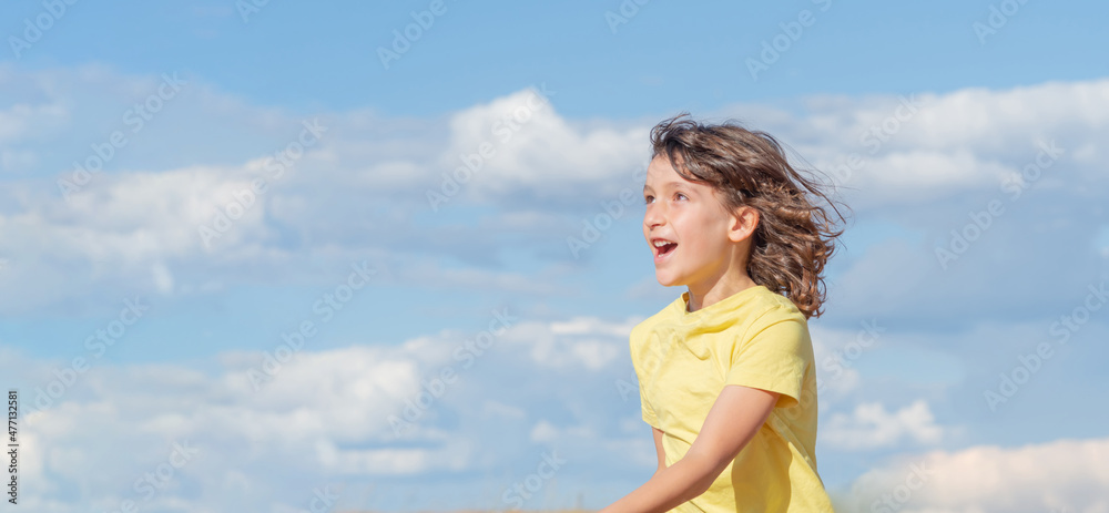 Young handsome boy looking up while laughing jumping and playing. blue sky background. copy space Young handsome boy looking up while laughing jumping and playing. blue sky background. copy space
