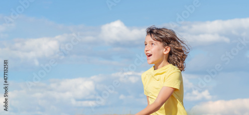 Young handsome boy looking up while laughing jumping and playing. blue sky background. copy space