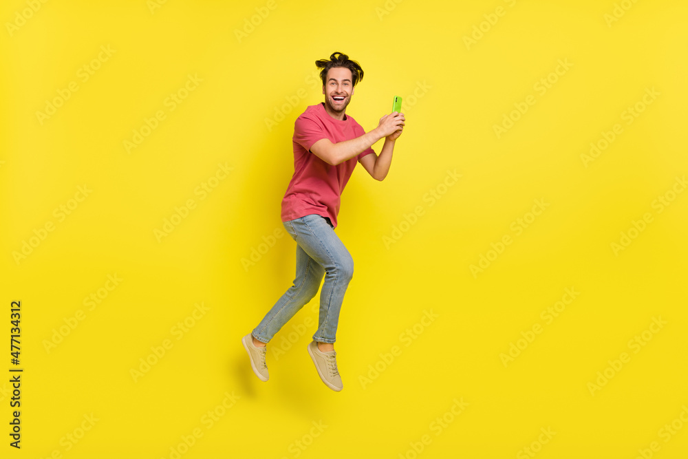 Full body profile photo of cool beard young guy run hold telephone wear red t-shirt jeans footwear isolated on yellow background Full body profile photo of cool beard young guy run hold telephone wear red t-shirt jeans footwear isolated on yellow background