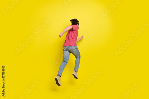Full length back photo of brunet millennial guy run away wear red t-shirt jeans shoes isolated on yellow background © deagreez