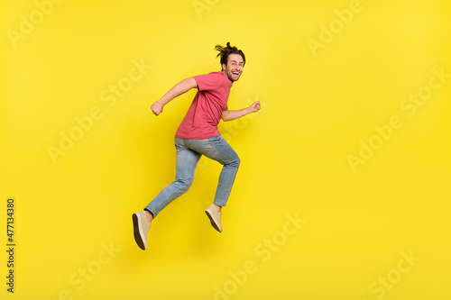 Full size profile photo of brunet young guy run wear red t-shirt jeans sneakers isolated on yellow background