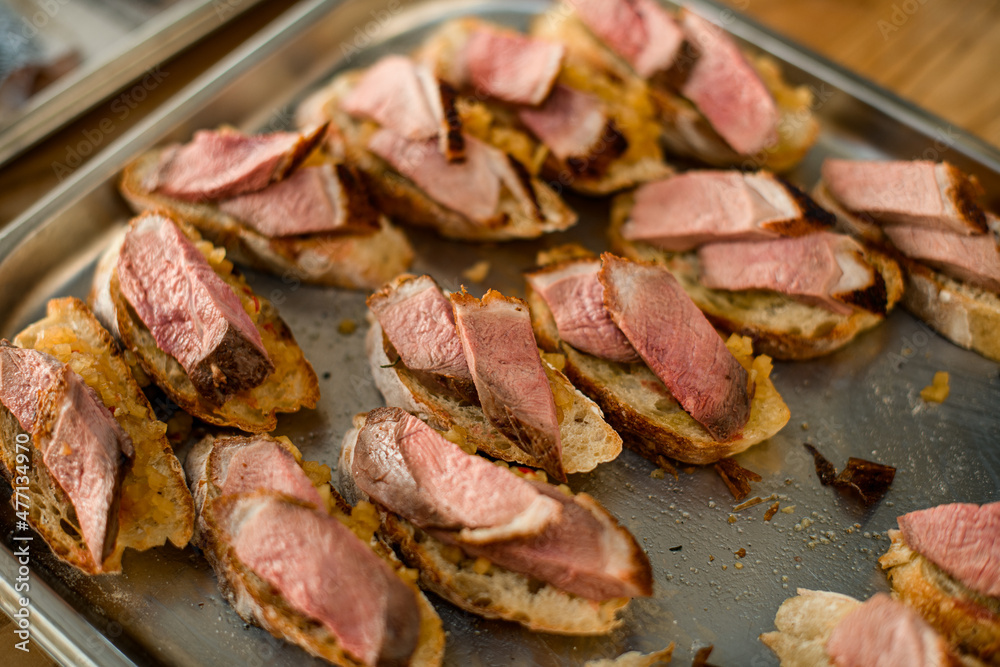 view of appetizer - slices of white baguette with blend vegetable and slices of meat on tray view of appetizer - slices of white baguette with blend vegetable and slices of meat on tray