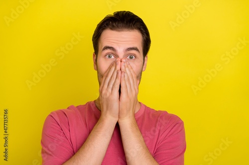 Photo of shocked surprised guy hands cover mouth omg reaction wear pink t-shirt isolated yellow color background
