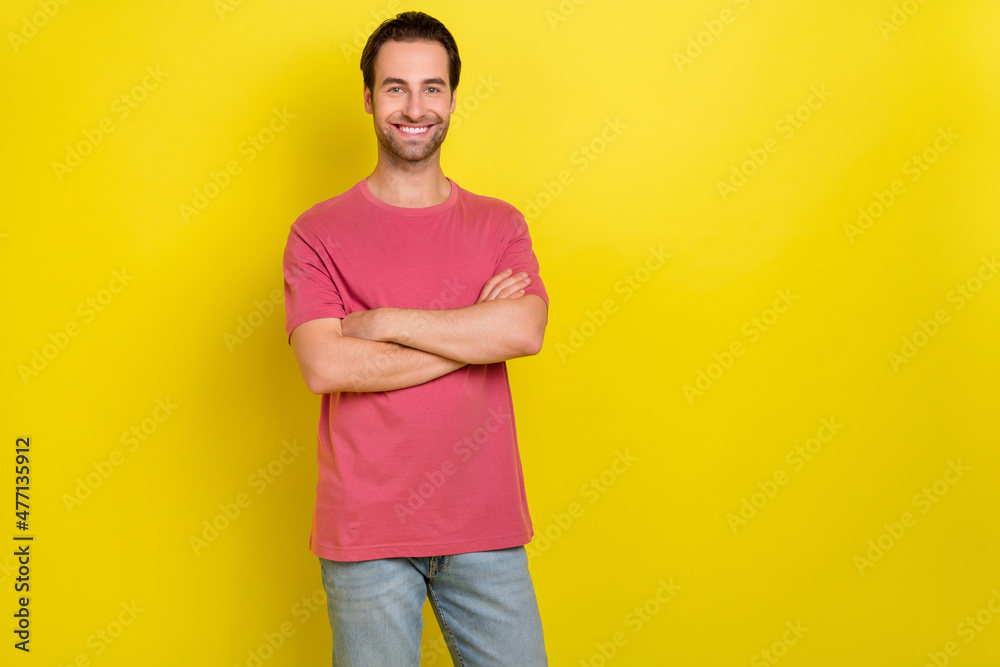 Photo of positive glad guy folded hands beaming smile wear pink t-shirt jeans isolated yellow color background Photo of positive glad guy folded hands beaming smile wear pink t-shirt jeans isolated yellow color background