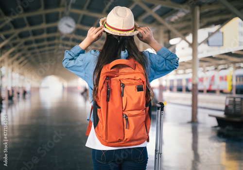 Woman traveler tourist with bag and hat at train station