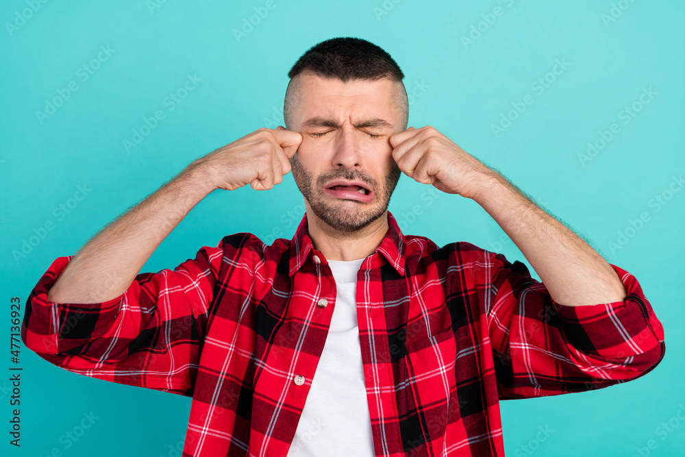 Photo of sad young brunet guy cry wear red shirt isolated on teal color background Photo of sad young brunet guy cry wear red shirt isolated on teal color background