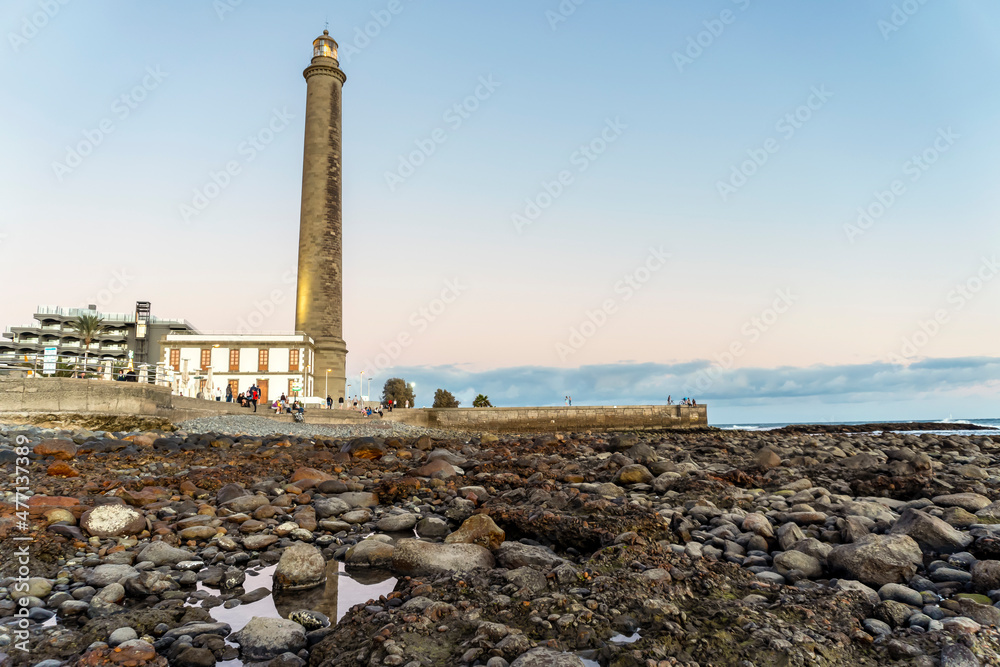 Fototapeta premium Lighthouse on rocky coast during sunset in Maspalomas, Gran Canaria, Spain