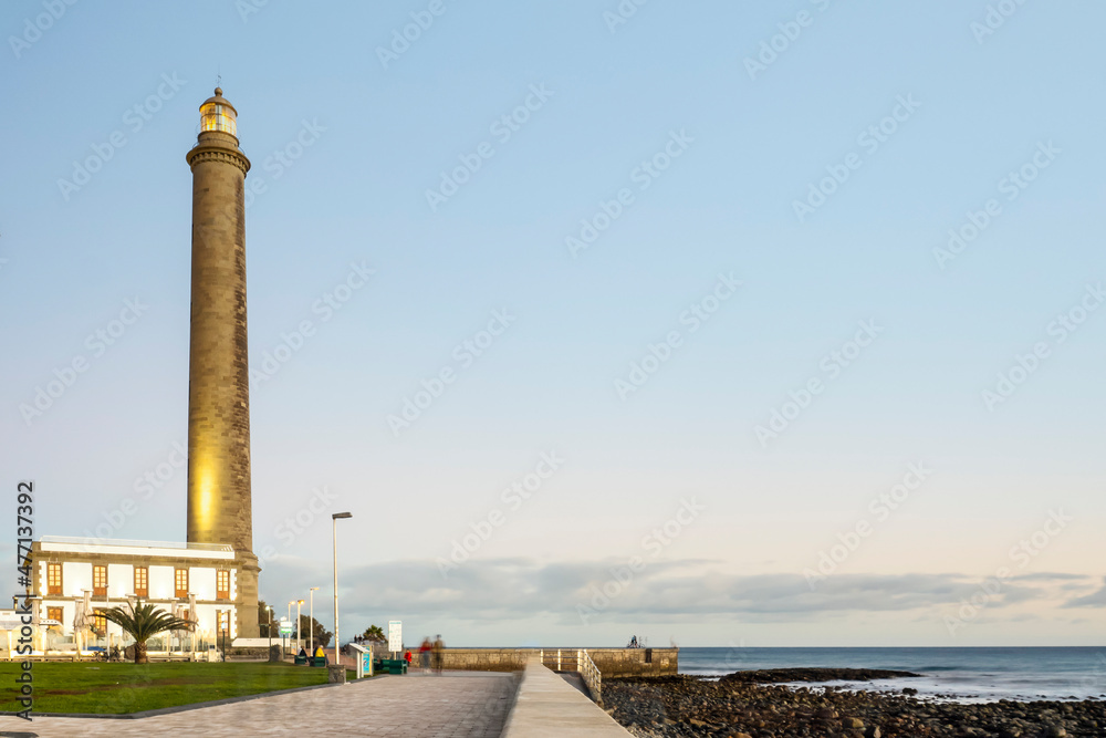 Fototapeta premium Lighthouse on rocky coast during sunset in Maspalomas, Gran Canaria, Spain