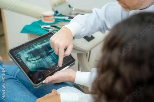 Dentist and patient commenting treatments in a tablet application in a consultation,Dentist and patient in dentist office.