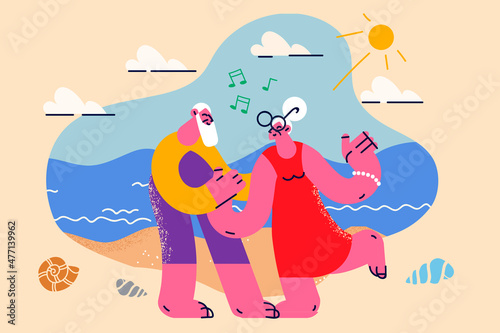 Happy old couple dance together on beach 