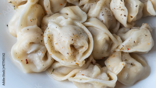 Boiled meat dumplings. Close-up view of russian boiled pelmeni on white plate.