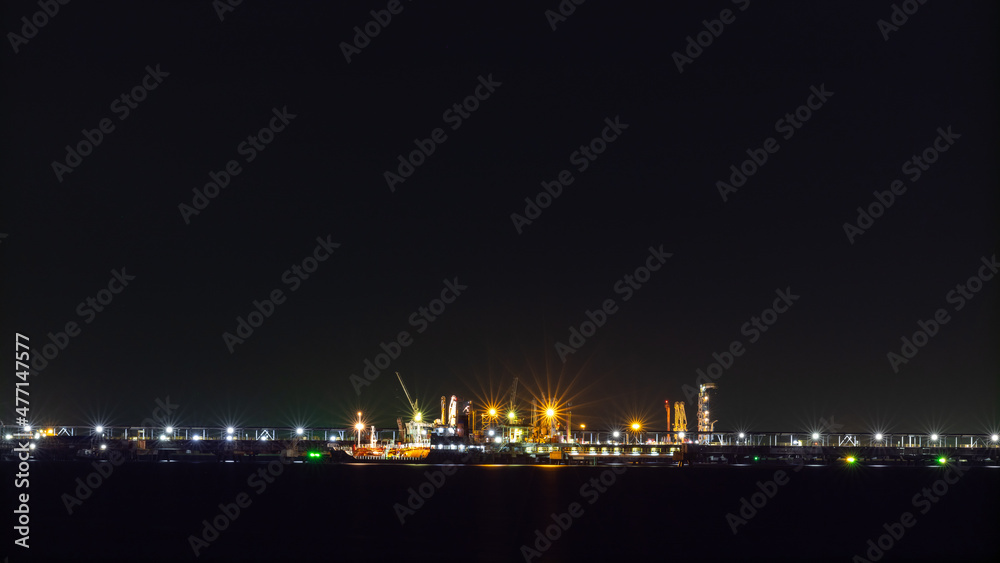 Oil ship tanker loading oil at the oil brige on the sea from refinery for transportation. at night over lighting in Thailand
