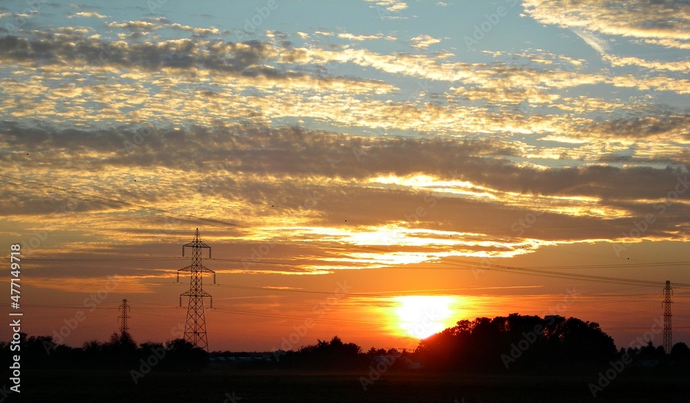 Italy, Lombardy: Sunset with silhouettes of electricity pylons.