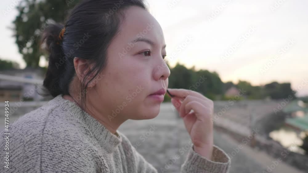 Close up of Asian woman sitting and getting good weather by the river Getting some fresh air. Sitting by the river.Trees background, looking beautiful view in the evening. Winter season Close up of Asian woman sitting and getting good weather by the river Getting some fresh air. Sitting by the river.Trees background, looking beautiful view in the evening. Winter season