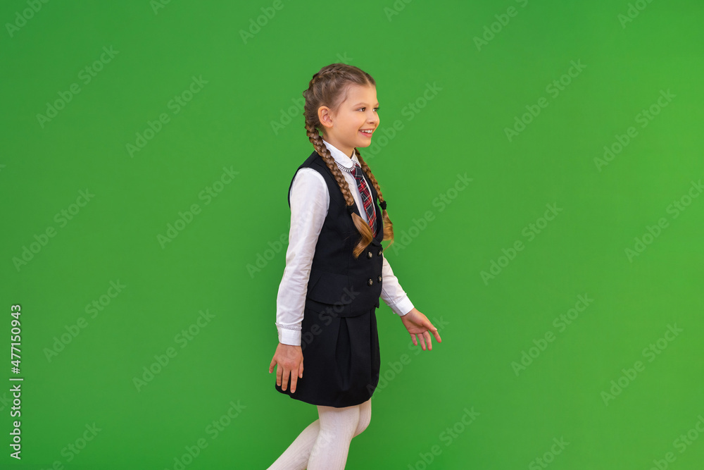 the child goes to school. getting an education in high school. a girl in a school uniform on a green isolated background. the child goes to school. getting an education in high school. a girl in a school uniform on a green isolated background.