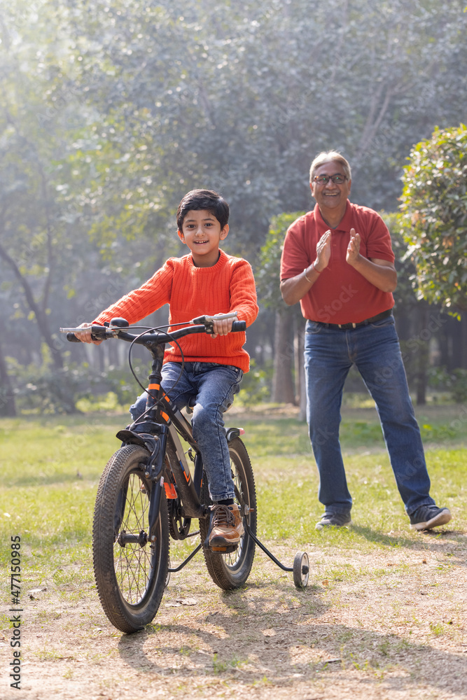 Fototapeta premium Grandfather teaching grandson riding bicycle at park 