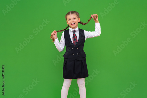 A beautiful smiling schoolgirl holds her pigtails. the girl likes school. isolated background . studying the school curriculum, craving for knowledge at school.