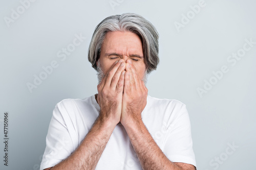 Photo of ill upset man pensioner dressed white t-shirt arms cover lips sneezing isolated grey color background