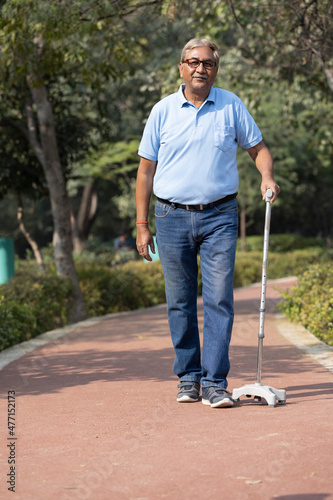 Canvas Print Senior man holding stick while walking at park