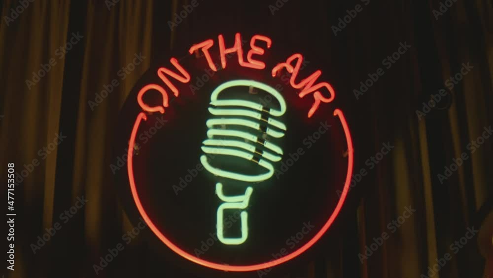 Retro style neon microphone sign hanging on the wall in club or pub . Colorful neon flashing lights on vintage speaker signboard or banner . Slow motion . Close up shot . Camera moving Retro style neon microphone sign hanging on the wall in club or pub . Colorful neon flashing lights on vintage speaker signboard or banner . Slow motion . Close up shot . Camera moving