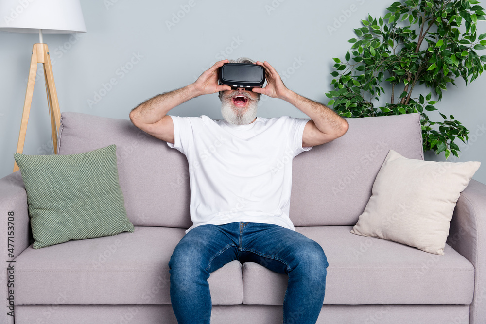 Portrait of attractive trendy cheerful gray-haired man playing wearing device free time isolated over grey pastel color background Portrait of attractive trendy cheerful gray-haired man playing wearing device free time isolated over grey pastel color background