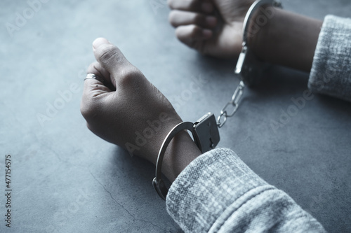 Photo man's hand with handcuff on black background.