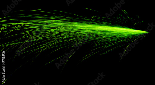 green fast-flying sparks from angle grinders on black background
