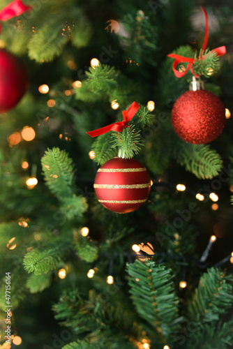Beautiful Christmas tree with decor against blurred lights on background. Merry Christmas, hello winter, red ball and green fir. 