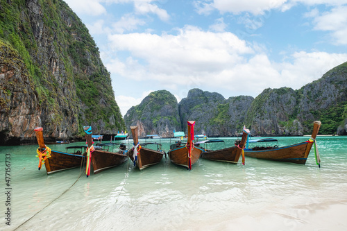 Wooden long-tail boats anchored on Maya Bay with limestone mountain range and turquoise sea in Phi Phi island at Krabi, Thailand © Mumemories