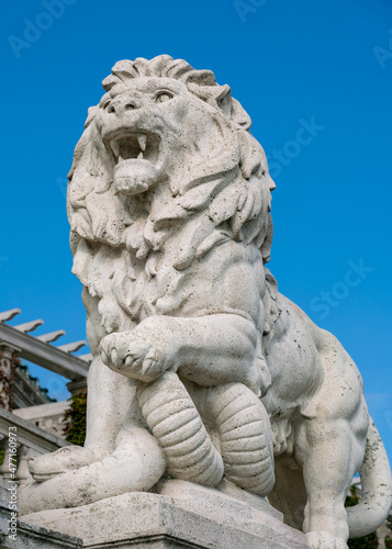 Roaring lion statue in white marble against clear blue sky, Budapest