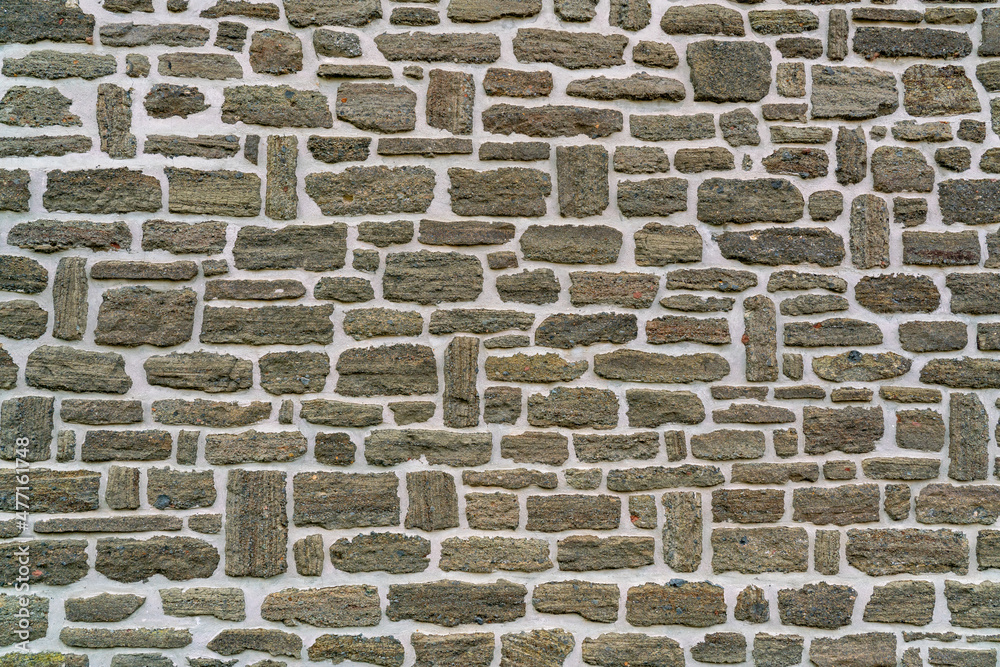 Stone wall pattern of grey brown rock in neat rows with white mortar in high resolution Stone wall pattern of grey brown rock in neat rows with white mortar in high resolution