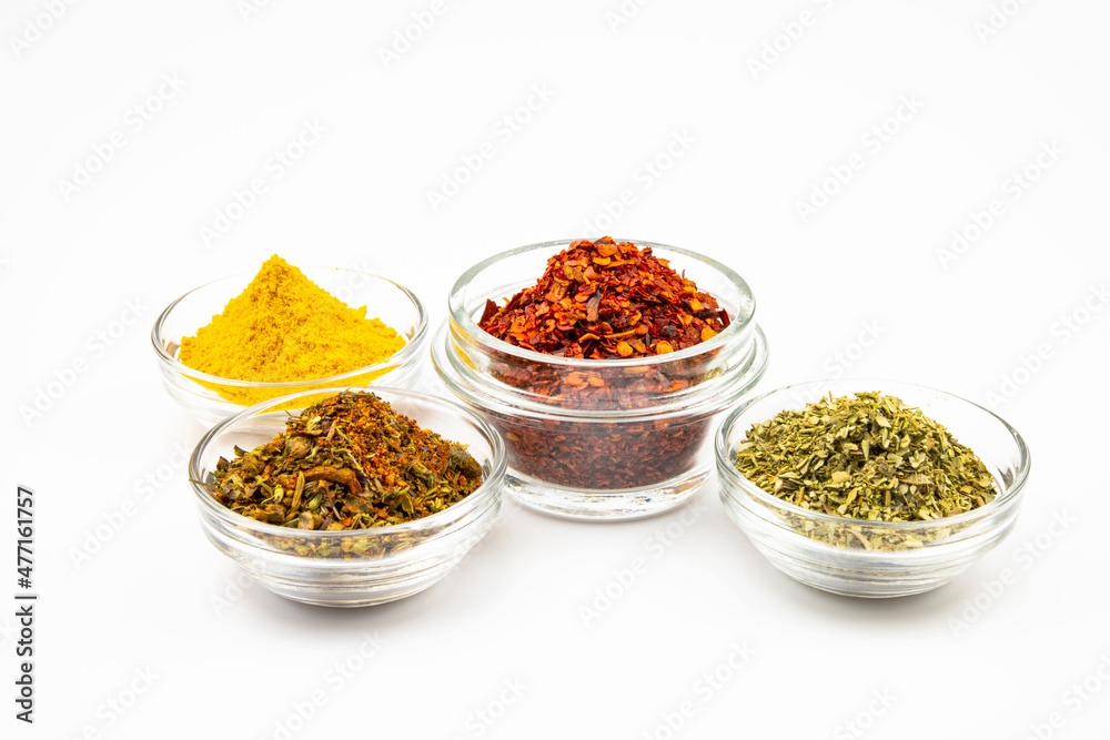Glass bowls of spices and seasonings isolated on a white background. Glass bowls of spices and seasonings isolated on a white background.