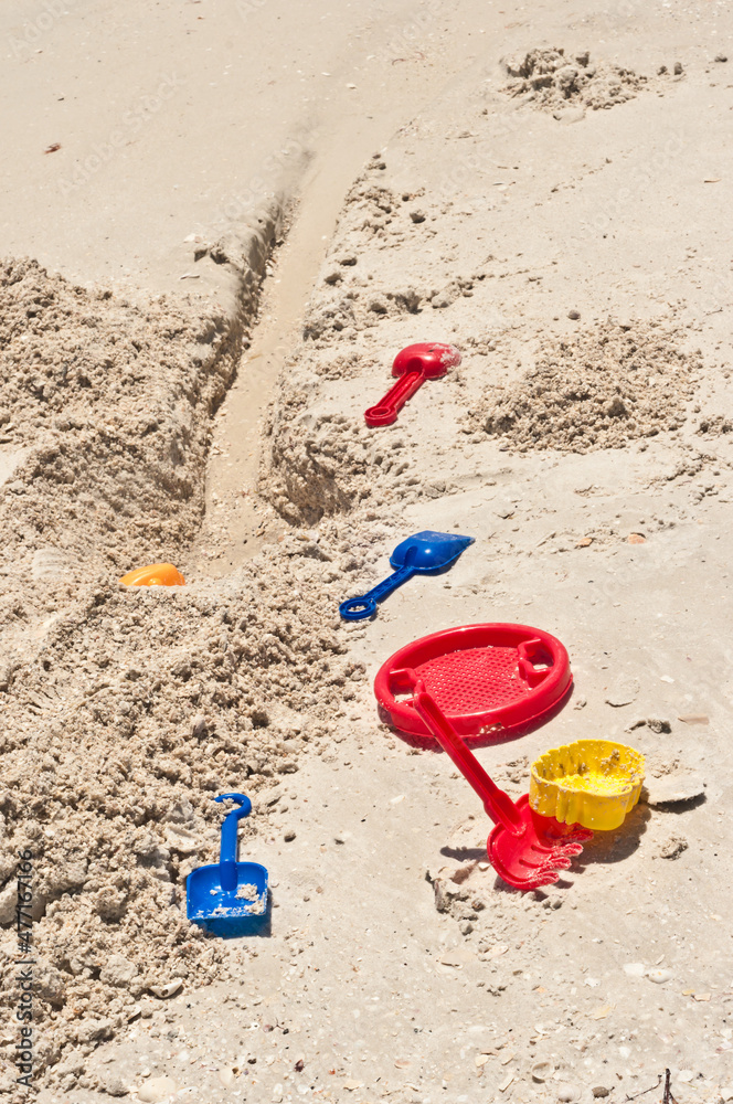 top view, medium distance, of child's plastic, colorful, beach toys, on a sandy, tropical, beach top view, medium distance, of child's plastic, colorful, beach toys, on a sandy, tropical, beach