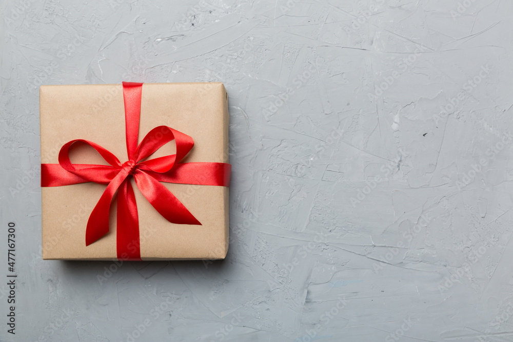 Holiday gift box wrapped in craft paper with colored bow on table background. Top view, flat lay, copy space Holiday gift box wrapped in craft paper with colored bow on table background. Top view, flat lay, copy space