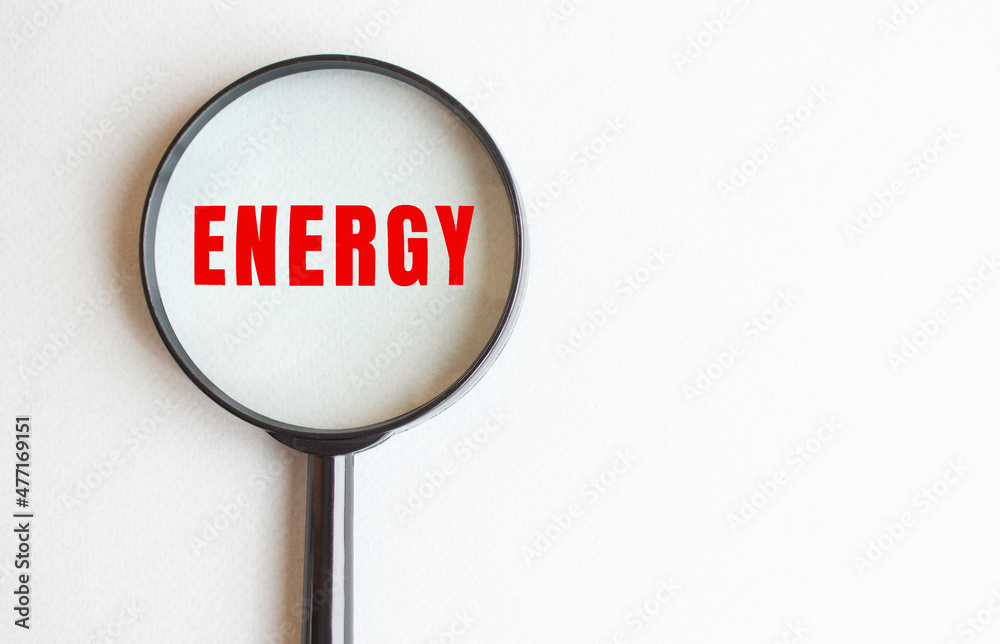 ENERGY text written on gray background. We read it through a magnifying glass. ENERGY text written on gray background. We read it through a magnifying glass.